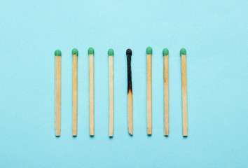Burned and whole matches on a blue background. Minimalism concept