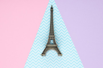 Fototapeta na wymiar Mini statuette of the Eiffel Tower on a pastel paper background. Top view