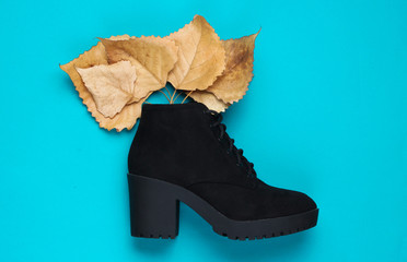 Black suede with fallen leaves on a blue background. Top view