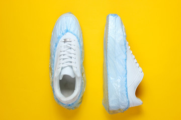 White sneakers in boot covers on a yellow background. Top view. Minimalism