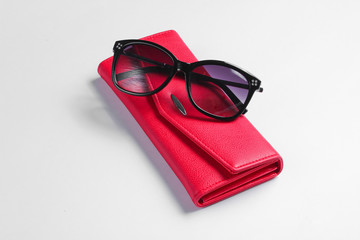 Red leather wallet, sunglasses closeup on white background