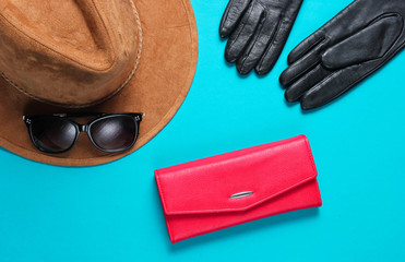 Fototapeta premium Women's fashion accessories. Red leather wallet, sunglasses, gloves close-up on blue background