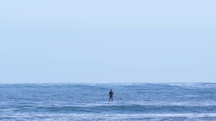 Surfer looking at horizon on blue ocean thinking with little waves. Nice weather with beautiful lights. Slow motion 100p. 4K UHD