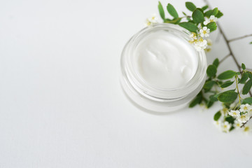 Obraz na płótnie Canvas mask in glass jar with flowers on white background copy space cosmetic hygiene cream beauty skin, face and body care moisture lotion wellness therapy . Top view.