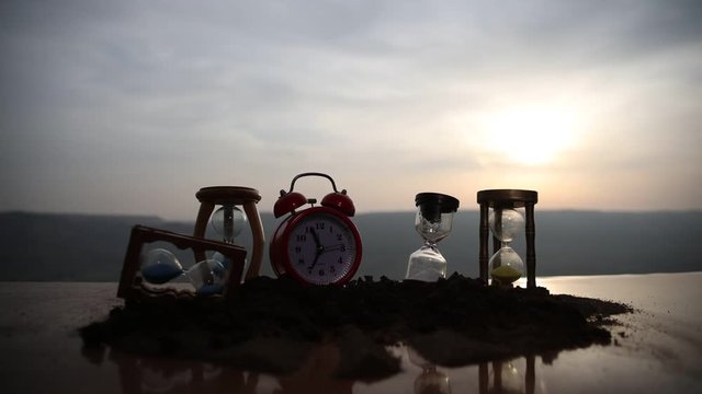 Time concept. Silhouette of Hourglass clock and smoke on blurred nature background at sunset time, or symbols of time under smoke, time ends or love ends. Optimistic or pessimistic ideas. 