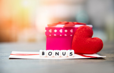 Yearly Bonus concept - card bonus in paper envelope with Gift Box surprise and Red heart for Encouragement Morale in table office company