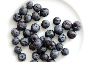 Fresh blueberry berries on a white plate close up. Top view