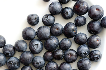 Fresh blueberry berries on a white plate close up. Top view