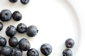 Fresh blueberry berries on a white plate close up. Top view