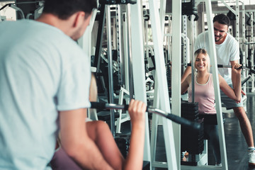 Fototapeta na wymiar Sporty Beautiful Woman in Fitness Exercise Training With Bodybuilder Equipment, Caucasian Woman is Working Out Exercising With Her Trainer Together in Gym Club. Sport Lifestyles and Healthy Concept