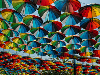 Fototapeta na wymiar colorful umbrellas outside as decor. umbrellas of different colors against the sky and the sun