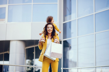 Beautiful girl in a summer city. Lady with shopping bags. Mother with daughter in stylish clothes