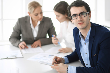 Group of business people discussing questions at meeting in modern office. Headshot of businessman at negotiation. Teamwork, partnership and business concept