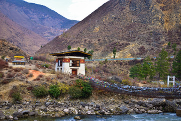 side view of walking suspension bridge with a lot of colorful prayer flags in Bhutan.