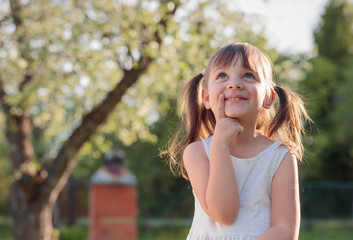 Happy little girl dreaming in the garden.