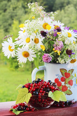 Fototapeta na wymiar A bouquet of wildflowers and a glass bowl of red currant