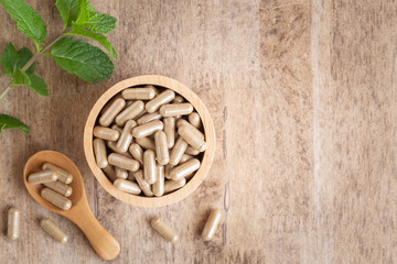 Herbal capsules  in cup on wooden table background . Top view of medicine for healthy and capsules...