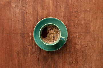 A cup of coffee on a dark rustic wooden background, shot from above with copy space