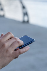 Close-up photo of human hand holding smartphone on the street.