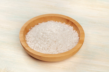 Fototapeta na wymiar A closeup photo of a bowl of sea salt on a white wooden background