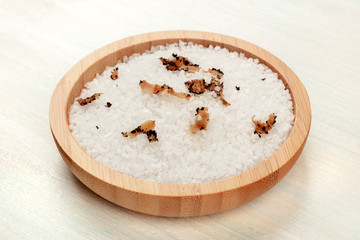 A bowl of sea salt infused with truffle shavings on a white wooden background
