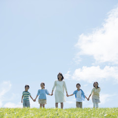 Fototapeta premium 草原で手をつなぐ小学生と先生