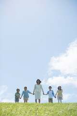 草原で手をつなぐ小学生と先生