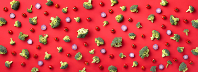 Creative layout of green broccoli, tomatoes, onion on red paper background. Top view. Food pattern in minimal style. Banner