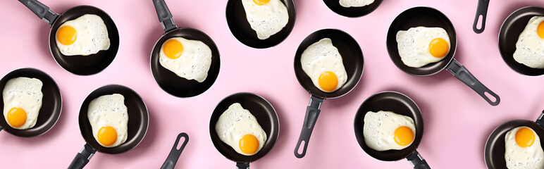 Creative food pattern with fried eggs on pans over pink background. Top view. Creative pattern in...