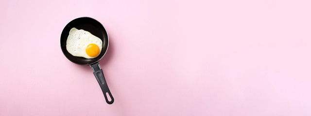 Creative food concept with fried egg on pan over pink background. Top view. Creative pattern in minimal style. Flat lay. Banner