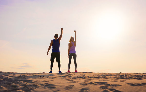 Fitness man and woman with arms up celebrating sport goals