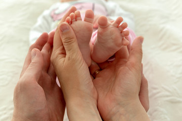 Closeup baby's feet in mother and father hands 