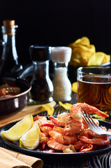 seafood at the bar, composition of black plate with shrimp lemon beer chips