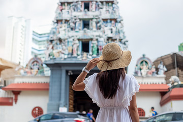 Woman traveling with white dress and hat, happy Asian traveler looking to Sri Mariamman Temple in Chinatown of Singapore. landmark and popular for tourist attractions. Southeast Asia Travel concept