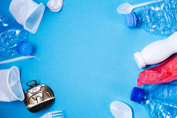 Plastic trash on blue background, eco concept image with copy space.