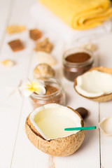 Coconut, spa products, coffee scrub, towels and seashells on white background