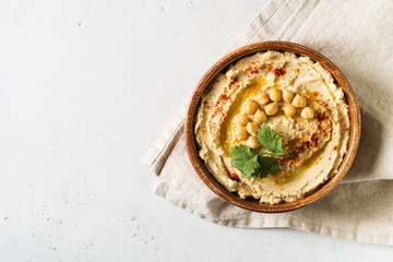 Hummus dip with chickpea, and parsley in wooden plate on white background - obrazy, fototapety, plakaty