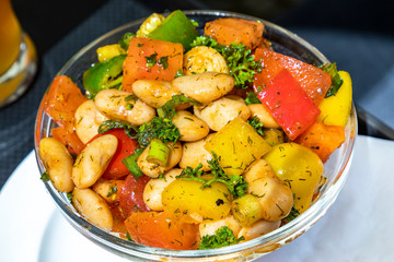 summer salad with tomatoes,beans,onions,paprika,oil,herbs in a glass bowl