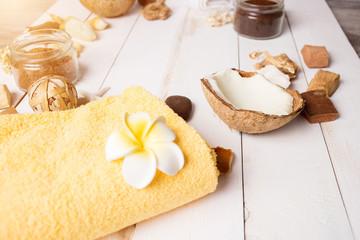Fototapeta na wymiar Coconut, spa products, coffee scrub, towels and seashells on white background