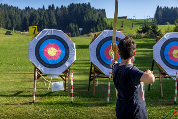 A very concentrated young boy practicing on Archery shooting