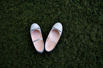 Silver girl's shoes with ribbon on the grass