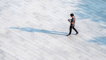 top aerial view people walk on across pedestrian concrete with black silhouette shadow on ground, concept of social still life. © ultramansk