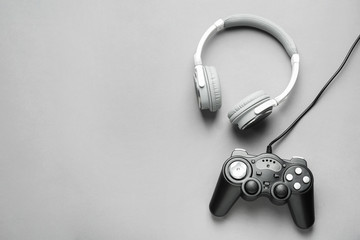 Modern game pad and headphones on grey background © Pixel-Shot