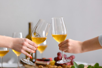 Friends clinking glasses with tasty wine at party