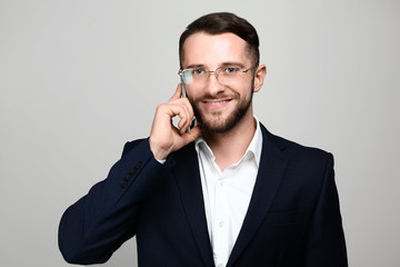 Handsome businessman talking by phone on light background