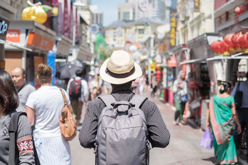 Fototapeta na wymiar Young man hipster traveling with backpack and hat, happy Solo traveler walking at Chinatown street market in Singapore. landmark and popular for tourist attractions. Southeast Asia Travel concept