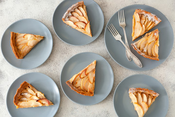 Plates with tasty apple pie on grey background