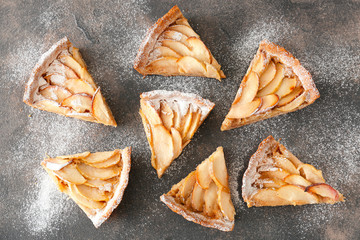 Pieces of tasty apple pie on grey background