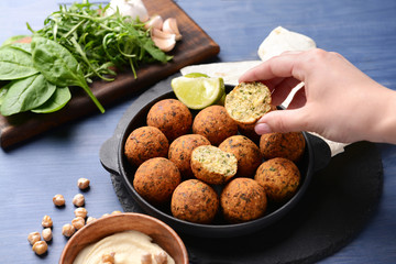 Woman eating tasty falafel balls at table