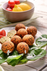 Plate with tasty falafel balls on wooden table
